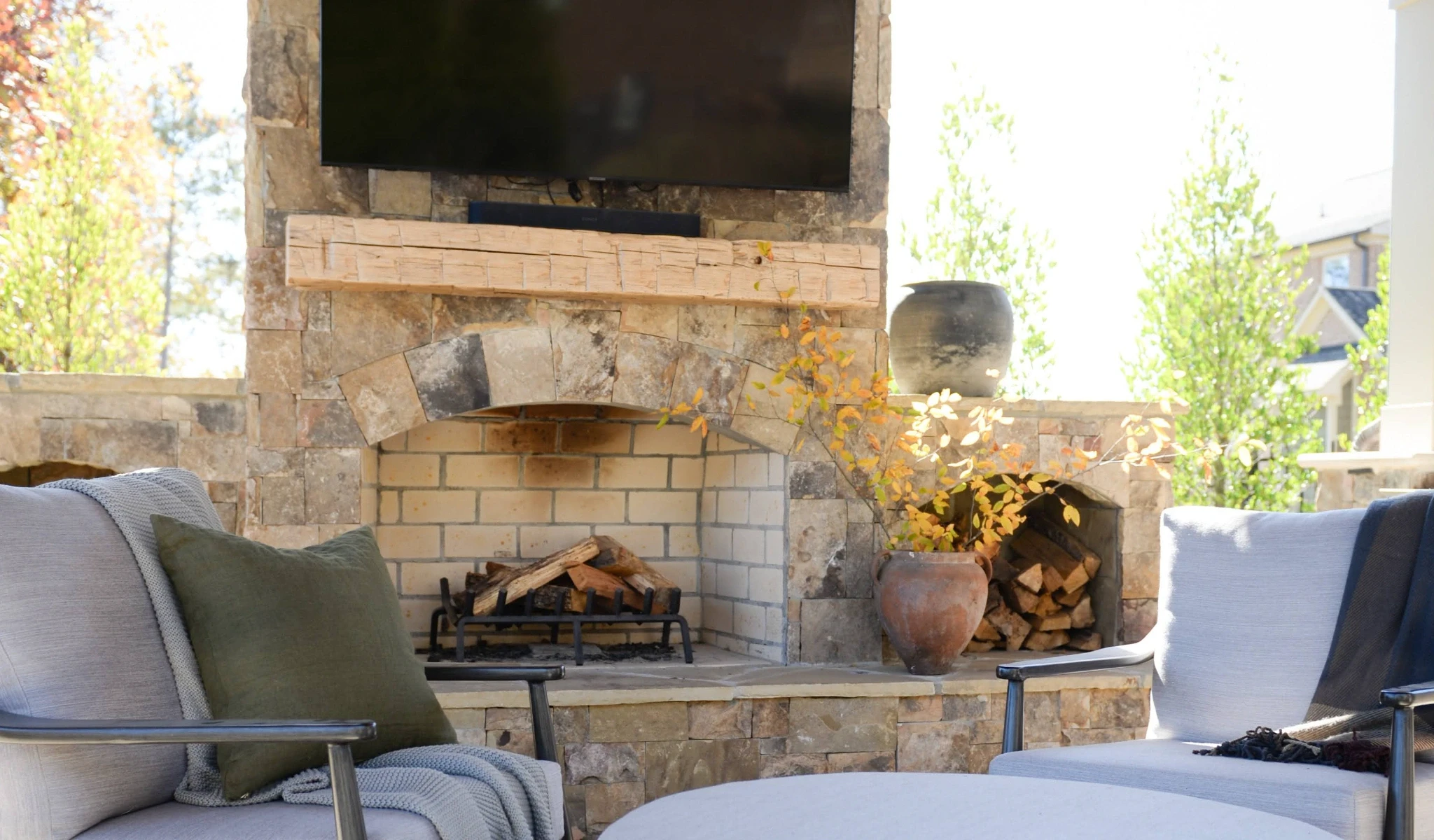An outdoor fireplace with a TV mounted above it, designed by a custom home builder.