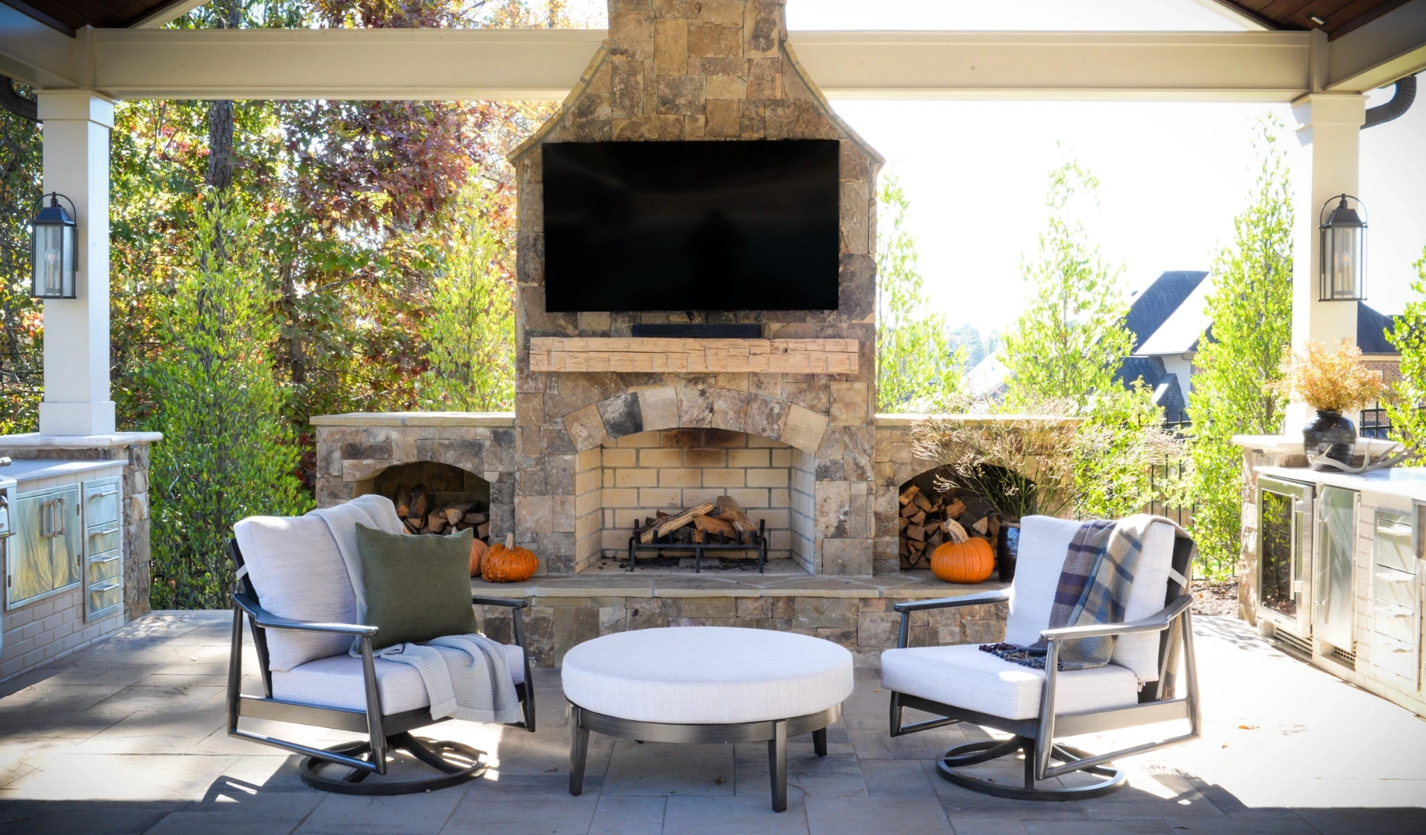 A patio with a fireplace, chairs, and a TV.