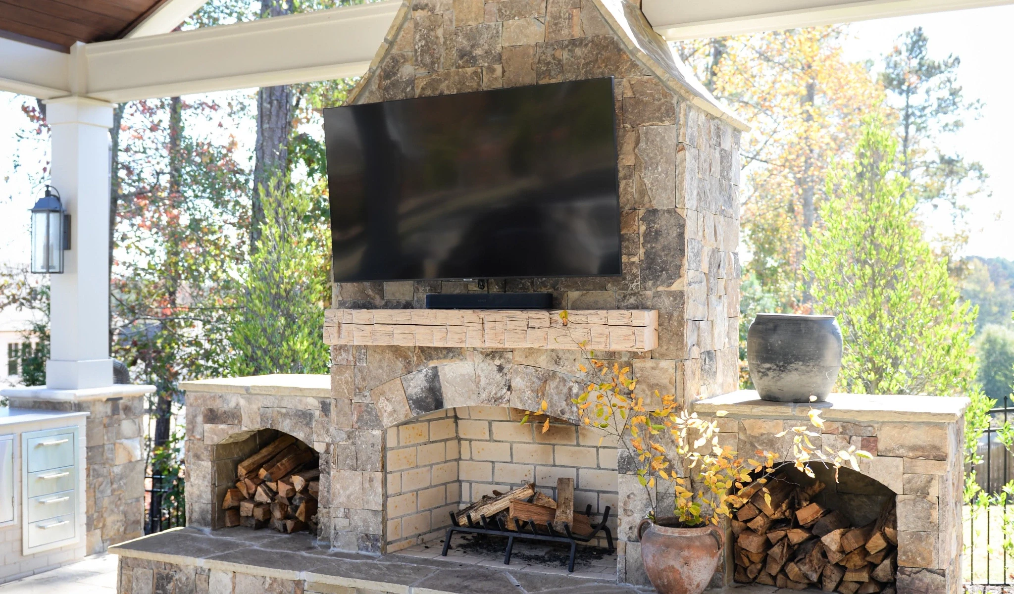 An outdoor stone fireplace with a TV above it.