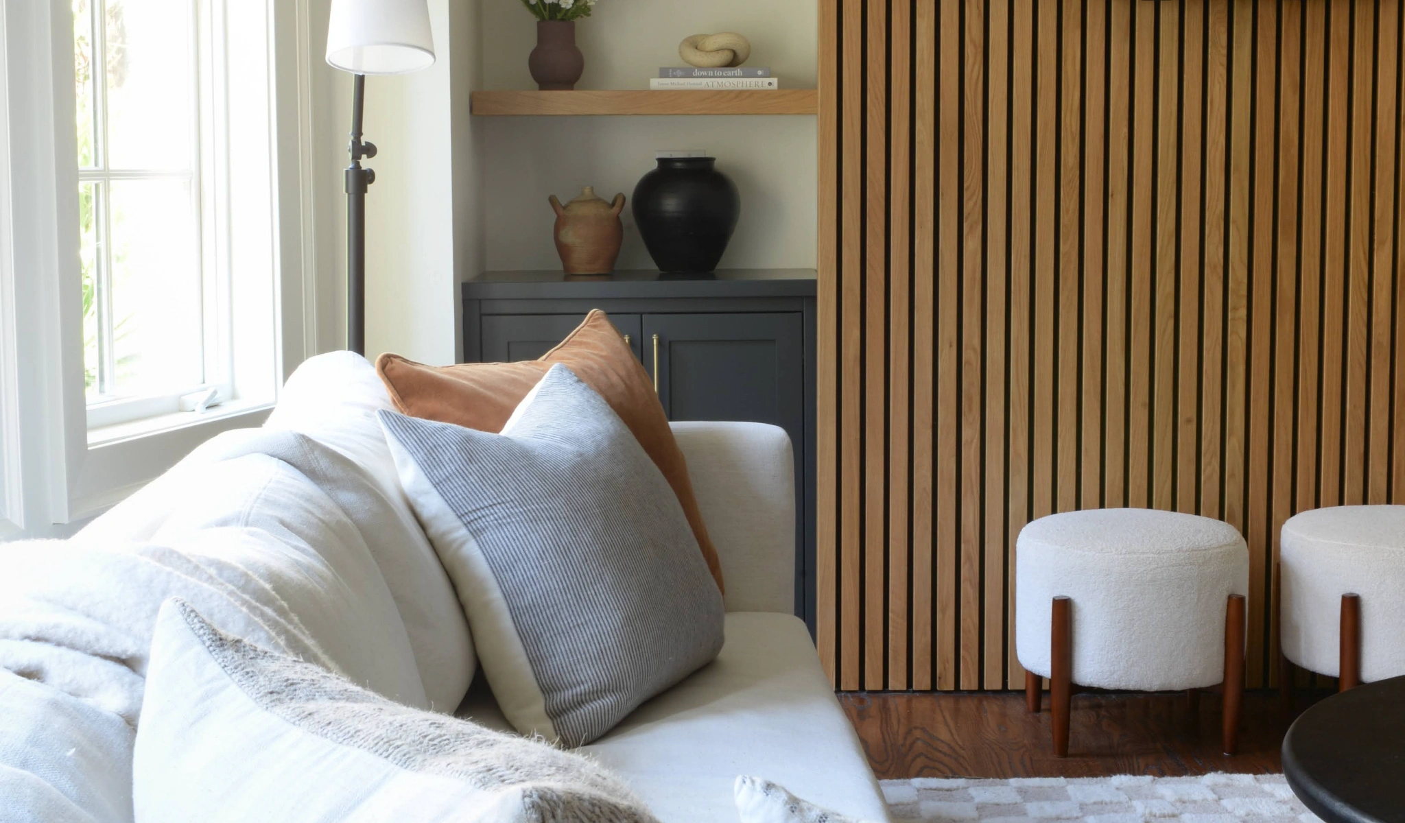 A living room with a wooden slat wall designed by a custom home builder.