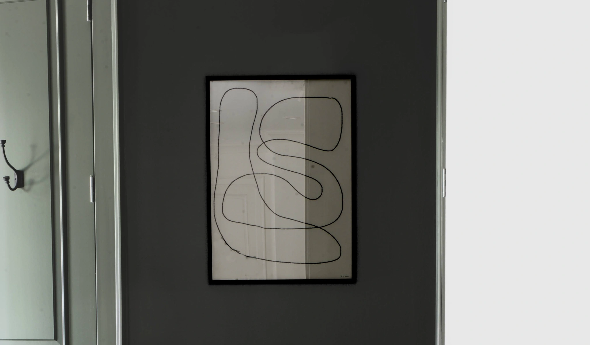 A black wall with a framed drawing on it.