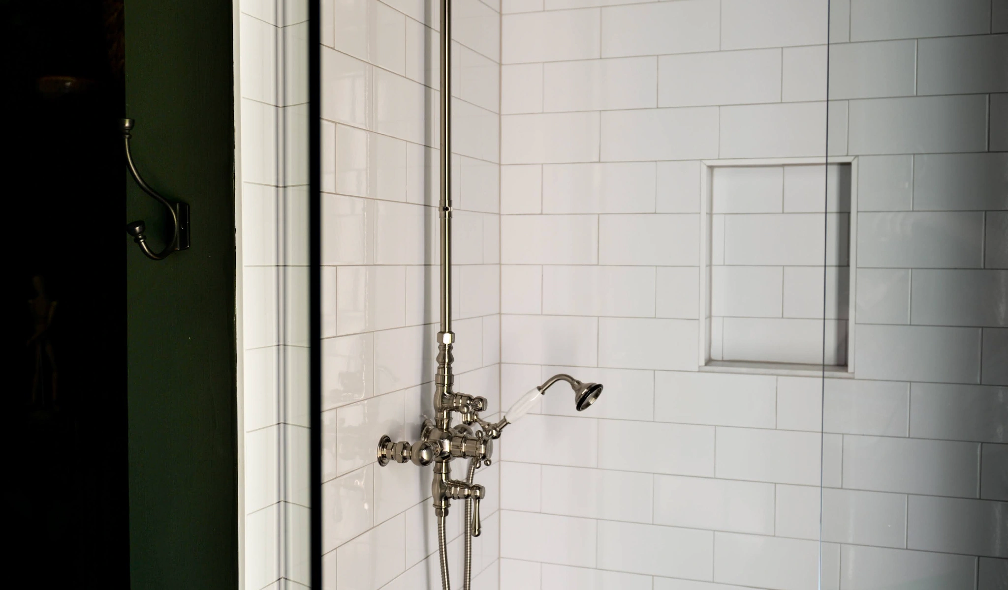 A white tiled shower with glass doors.