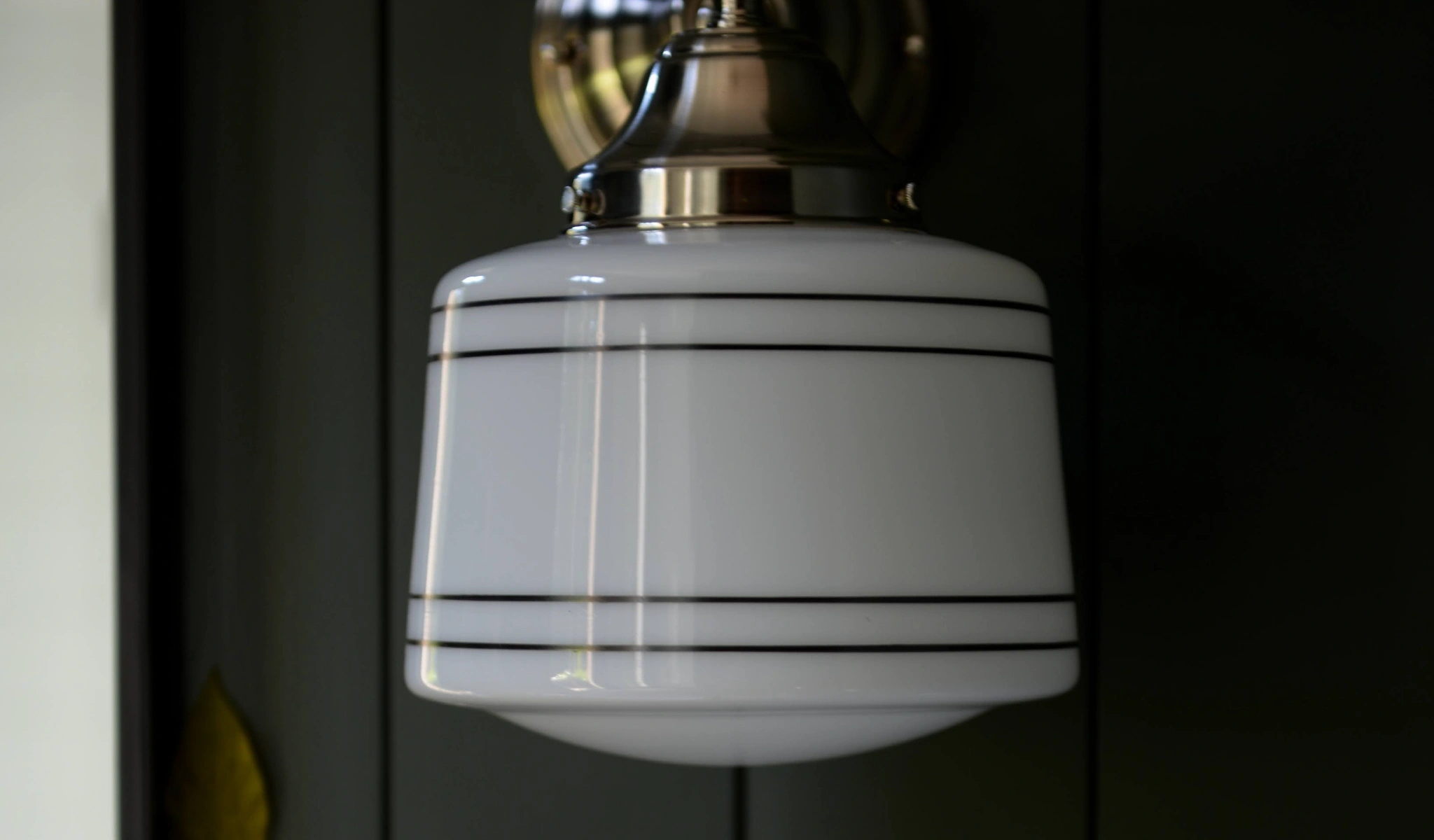A white sconce hanging on a black door.