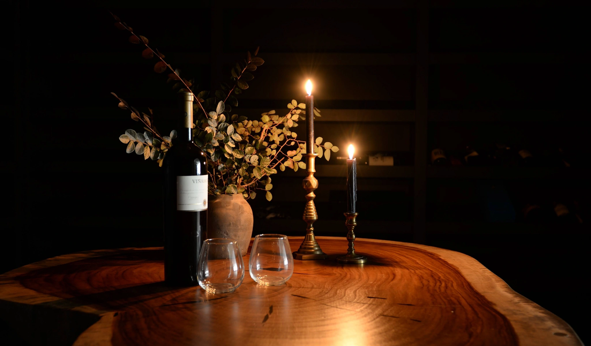 A bottle of wine and a glass of wine on a wooden table, perfect for home entertaining.