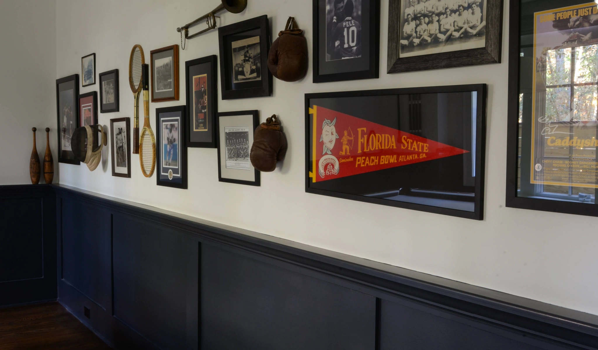 A black wall adorned with numerous framed pictures, designed by a home designer.