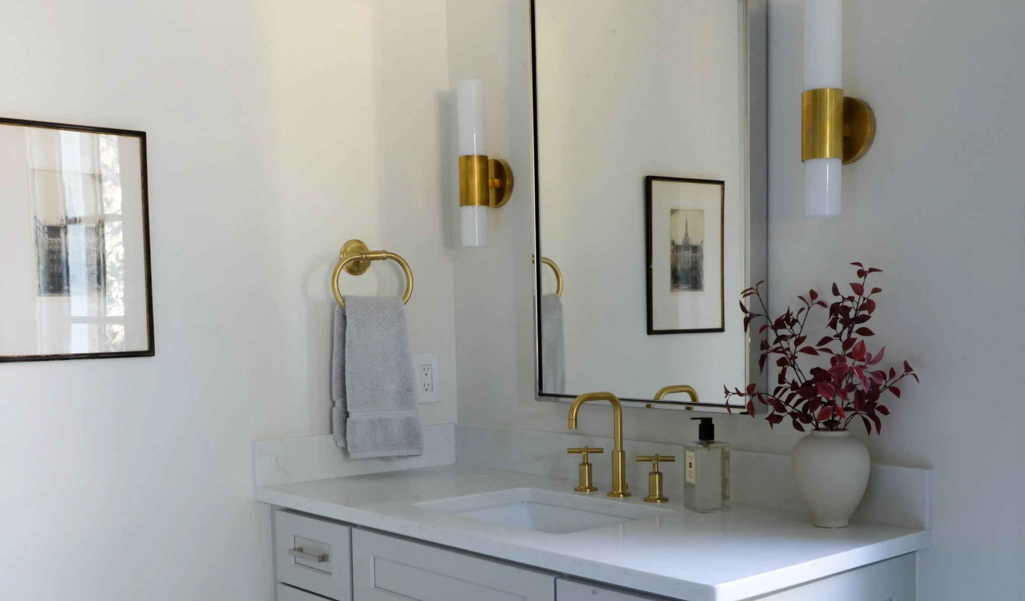 A white bathroom features a luxurious gold vanity and mirror.
