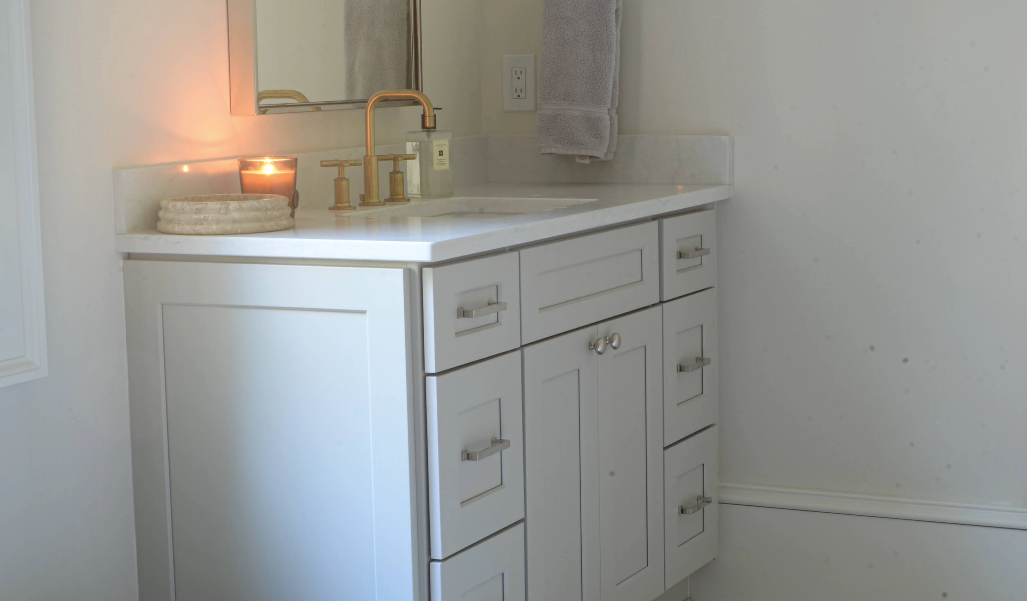 A white bathroom vanity with a candle.