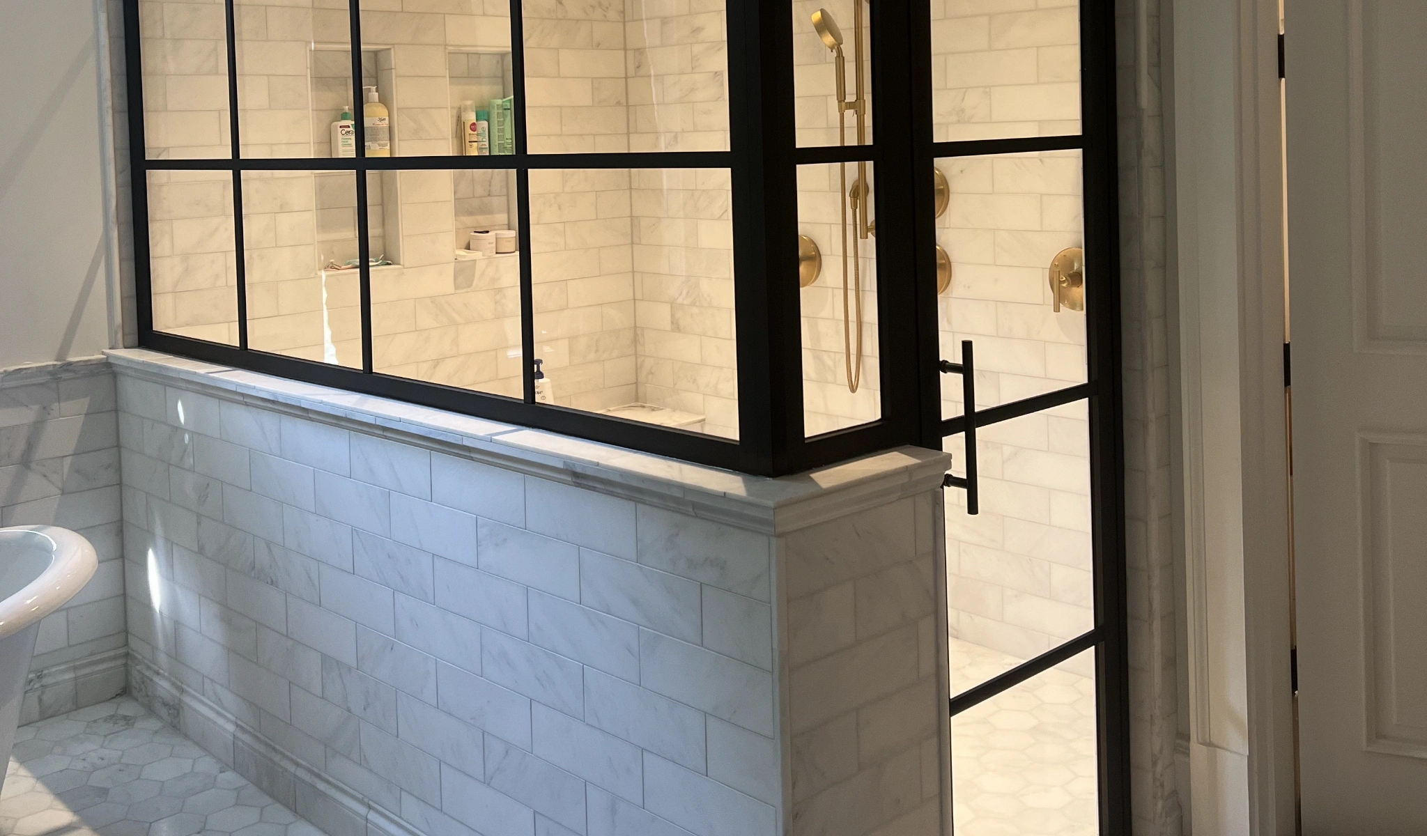 A bathroom with a glass shower door constructed by home builders.