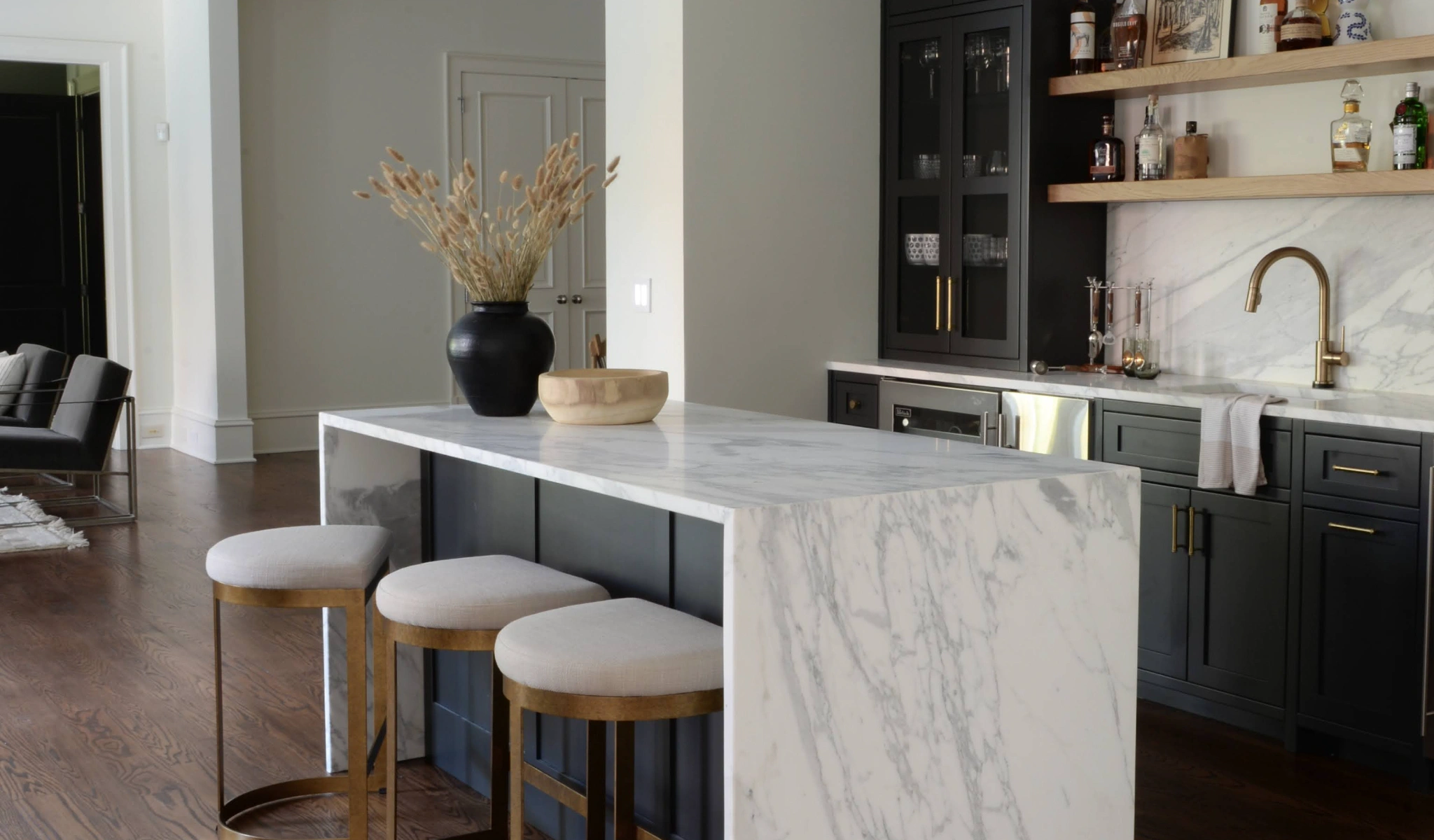 A kitchen with a marble counter top and bar stools.