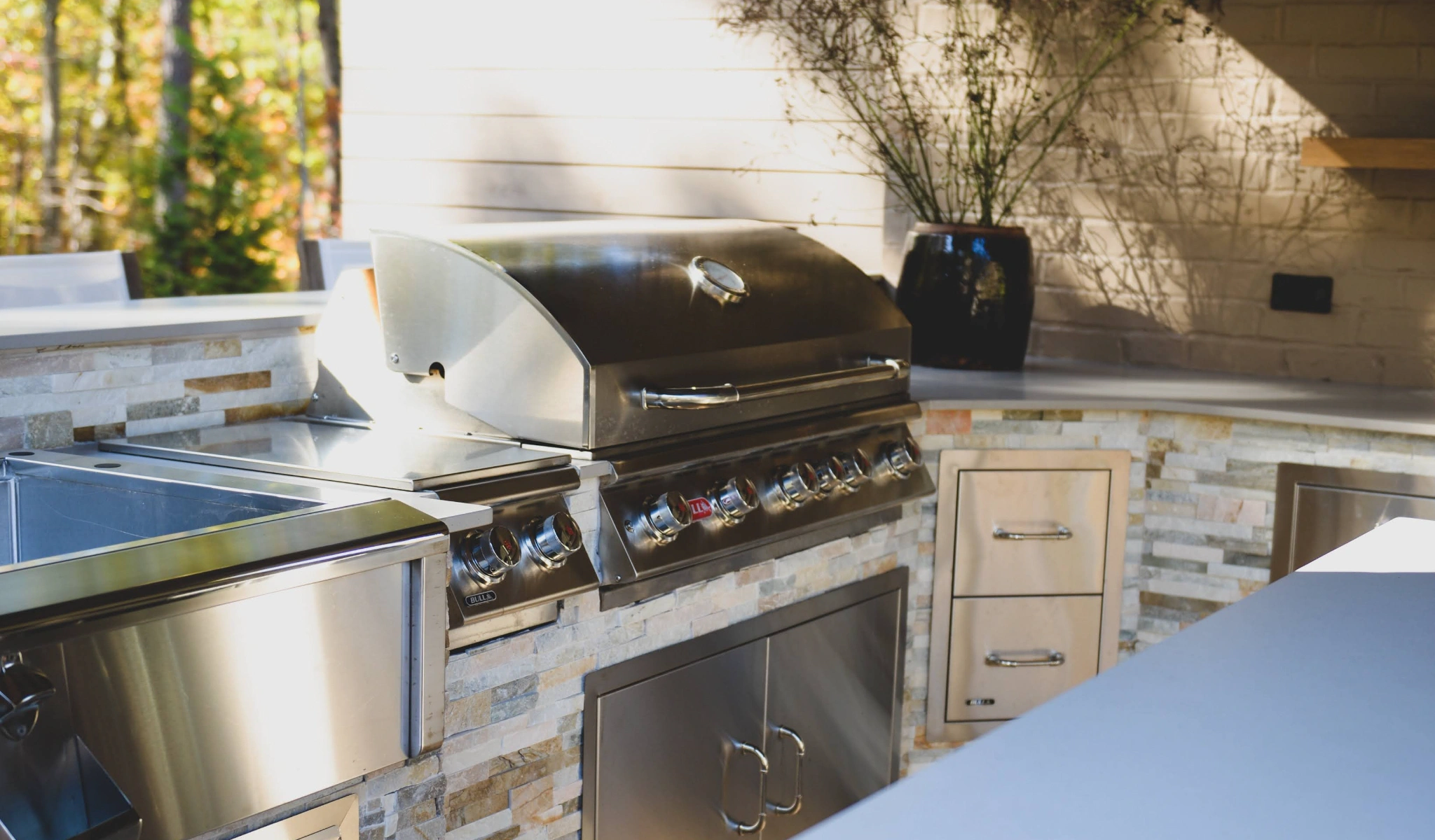 An outdoor kitchen with stainless steel appliances and stone details.