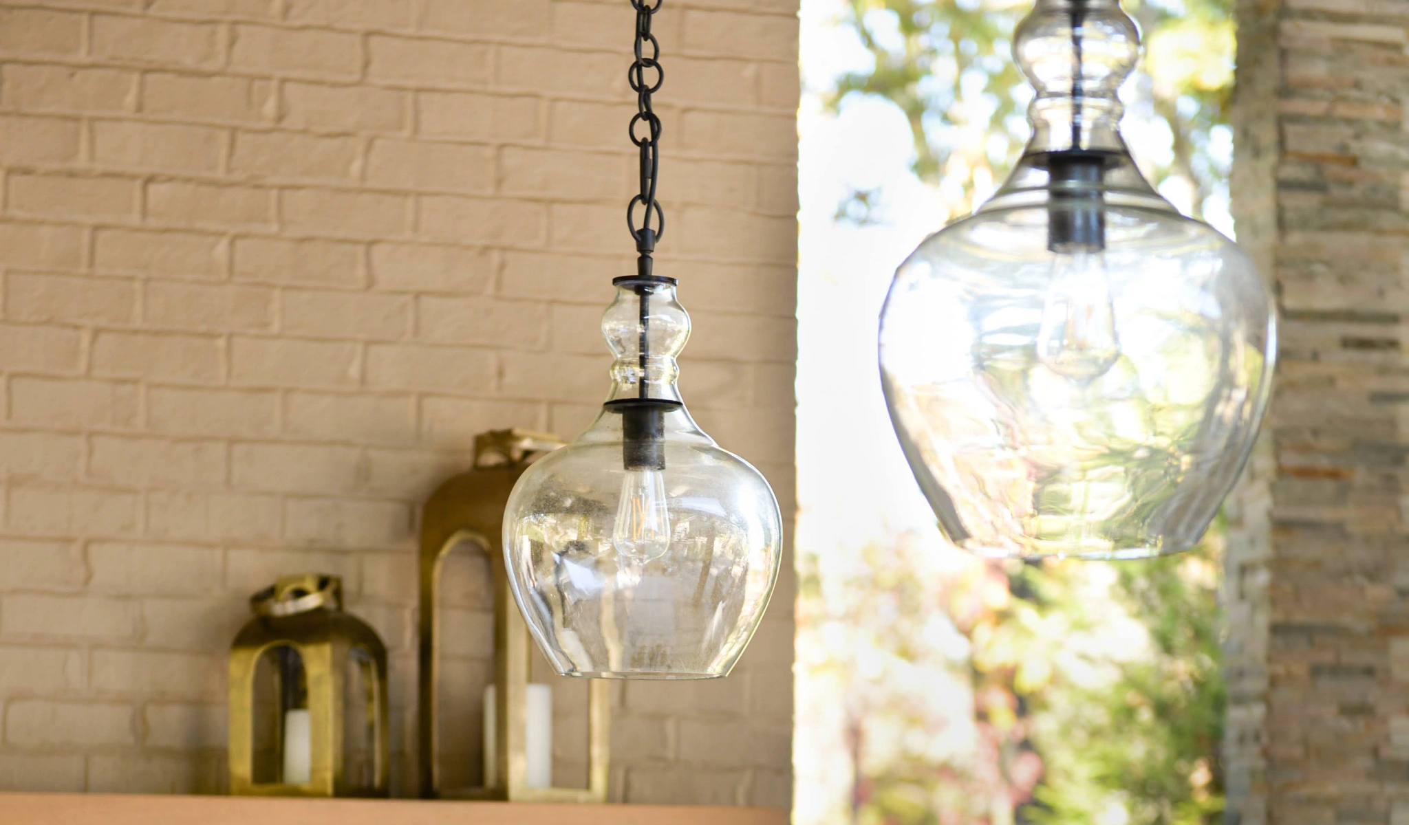 Two glass pendant lights in front of a brick wall.