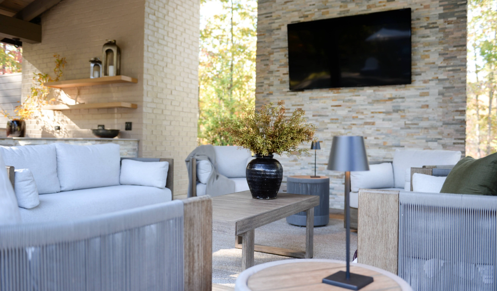 An outdoor living room with white furniture and a tv.