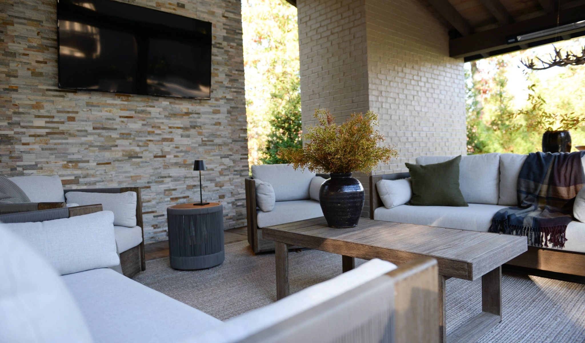 An outdoor living room with furniture and a TV, built by a custom home builder.
