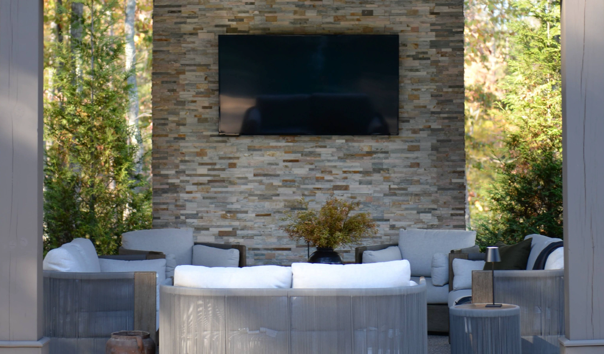 An outdoor living area with a TV mounted on a stone wall.