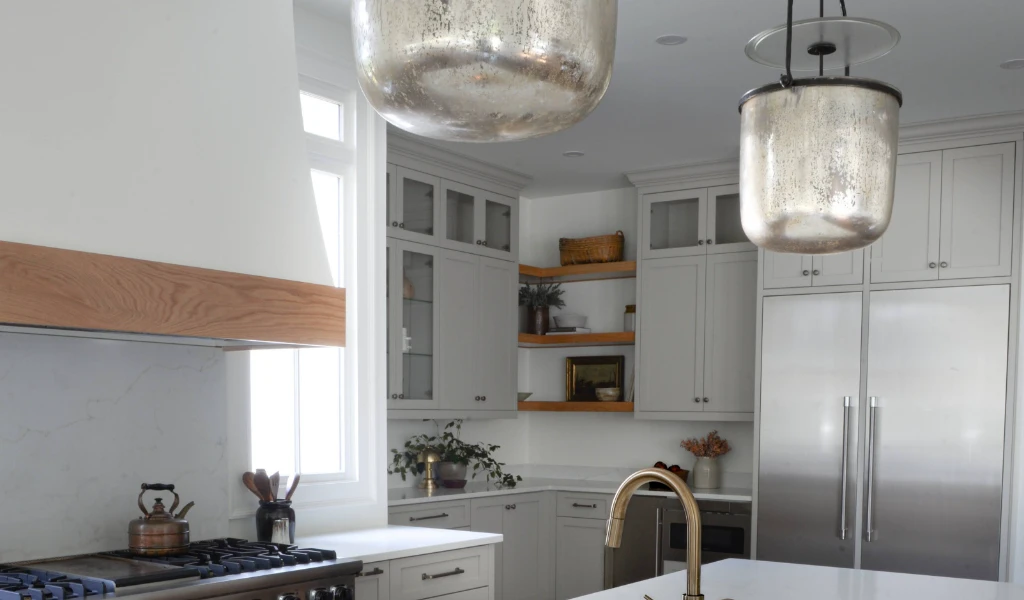 A white kitchen with a new island and pendant lights.