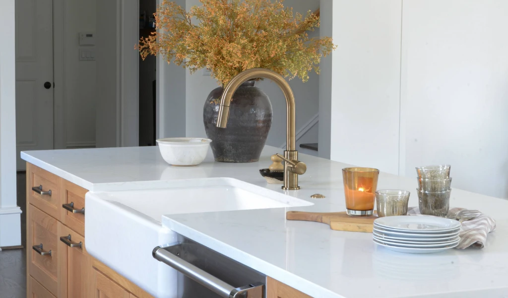 A white kitchen with a wooden island and a brass faucet.
