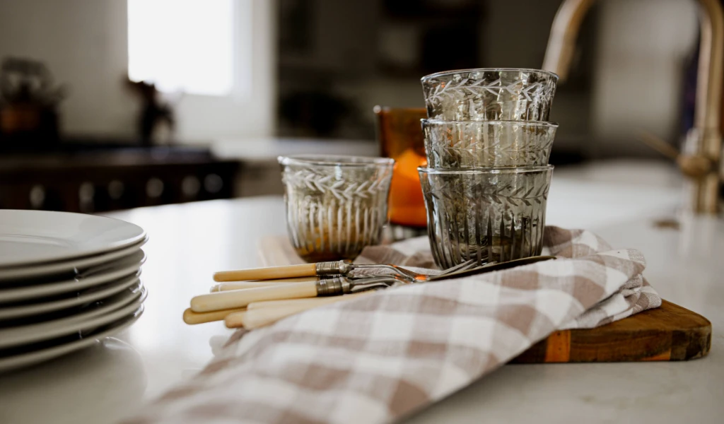 A set of glasses and utensils sit on a kitchen counter in a newly constructed home.