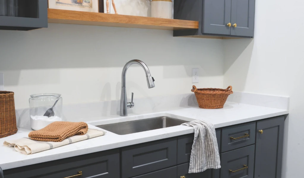 A laundry room with gray cabinets and a sink, designed by a home designer.