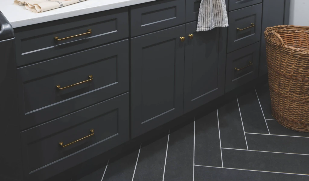 A laundry room with gray cabinets and a basket on the floor.