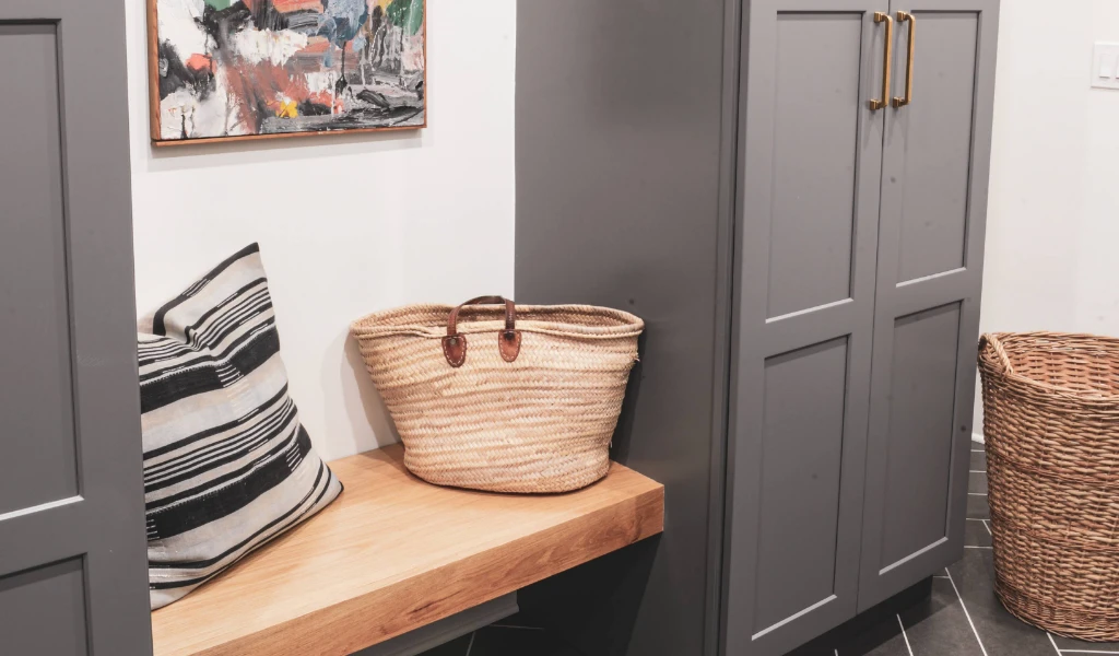A gray mudroom with a bench and basket.