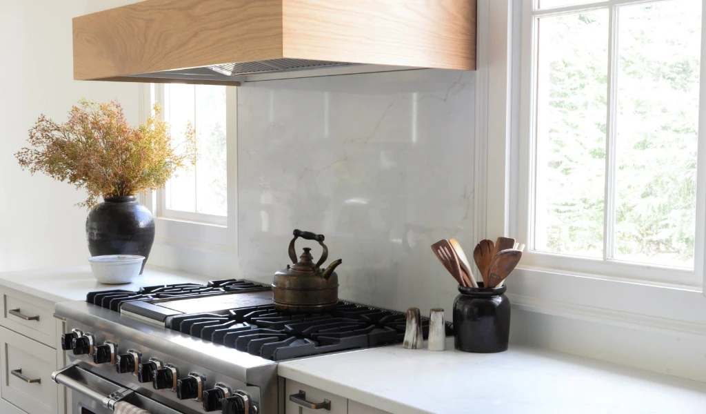 A white kitchen with a wooden hood over the stove.