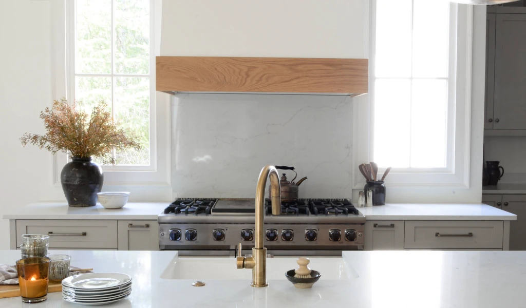 A kitchen with a white counter top and a gold faucet in a new home construction.