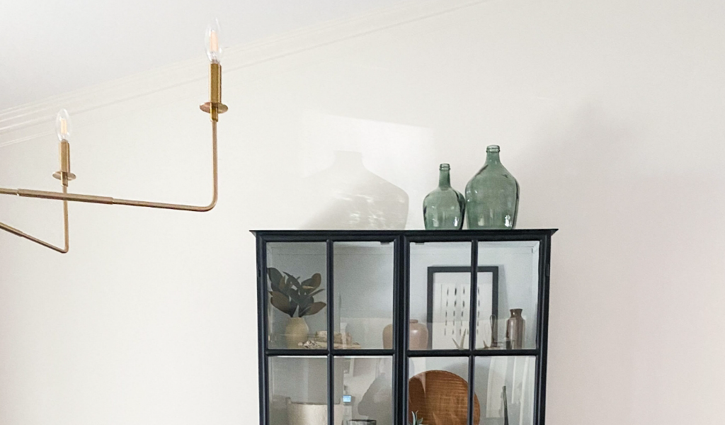A sleek black cabinet with glass doors and a gold chandelier.