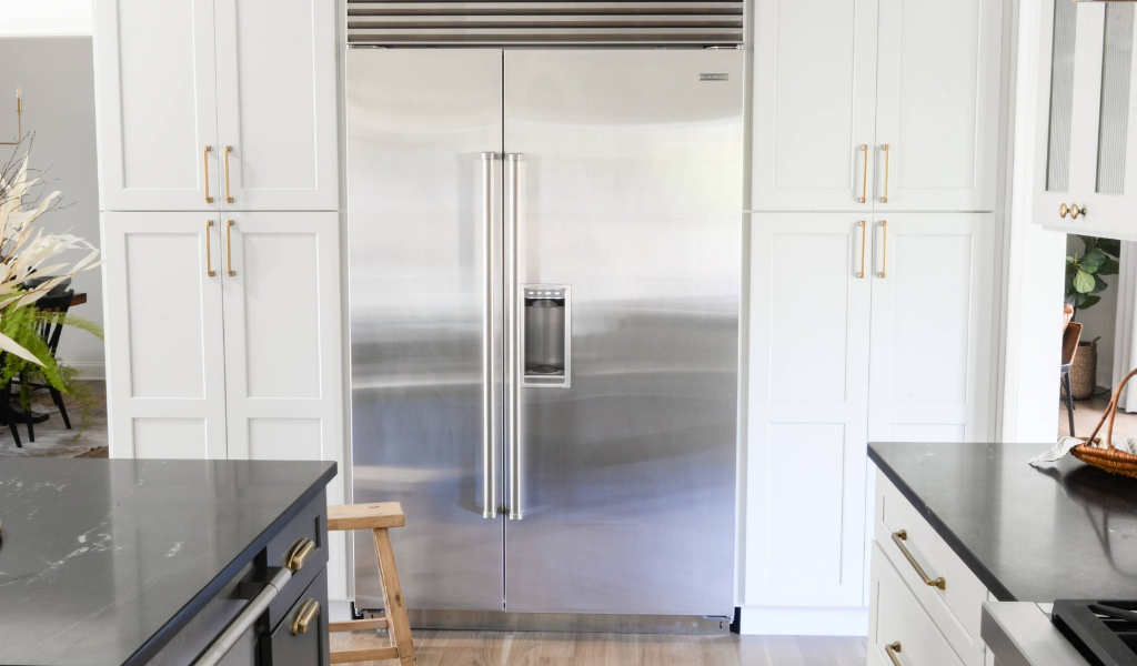 A white kitchen with a stainless steel refrigerator.