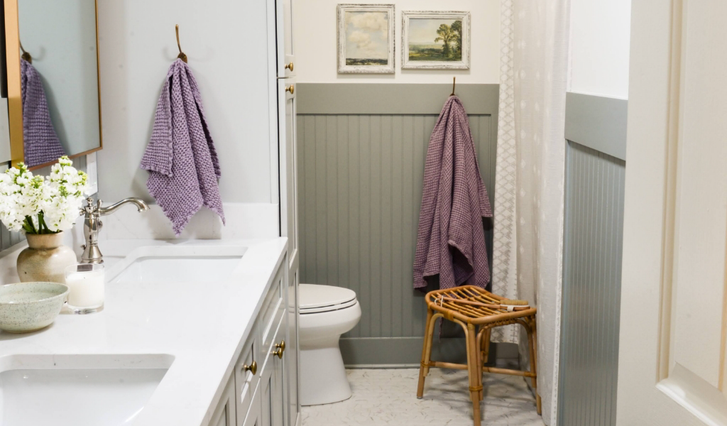 A white bathroom with purple towels hung on the wall.