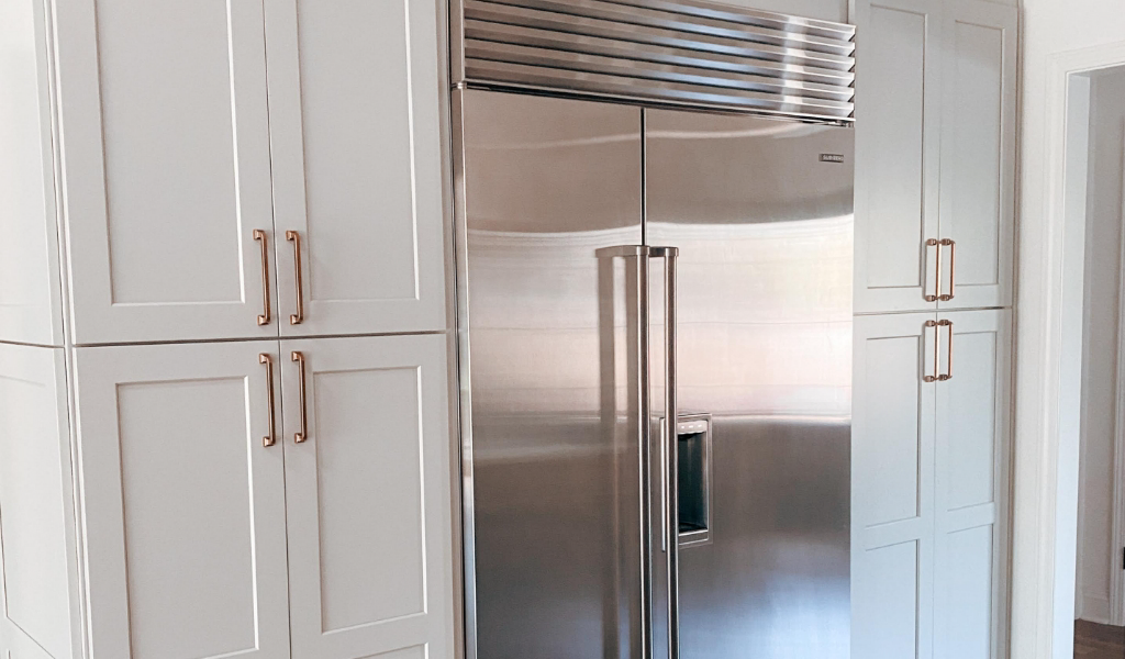 A kitchen with white cabinets and a stainless steel refrigerator.