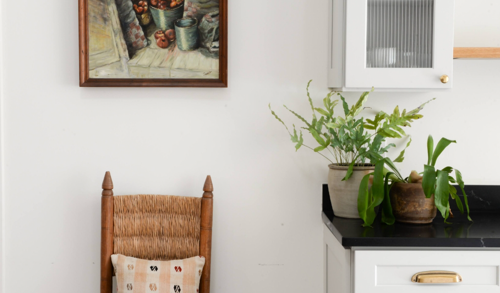 A kitchen with a wooden chair and a painting on the wall.