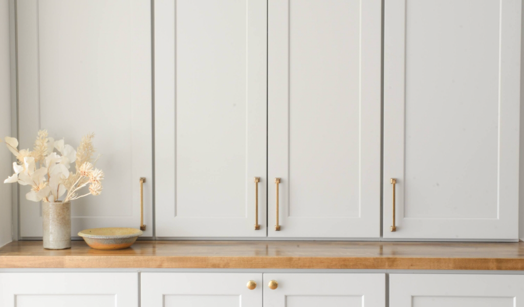 A kitchen with white cabinets and brass handles.