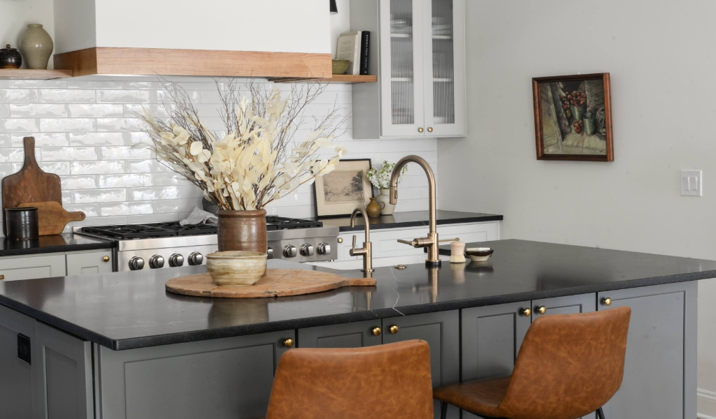 A kitchen with a black island and brown stools.
